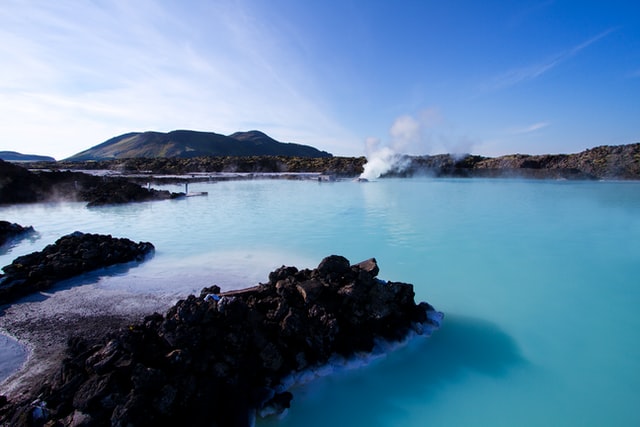 A hot spring in the Blue Lagoon Geothermal Spa in Iceland with steam coming off of the hot water into the cold air