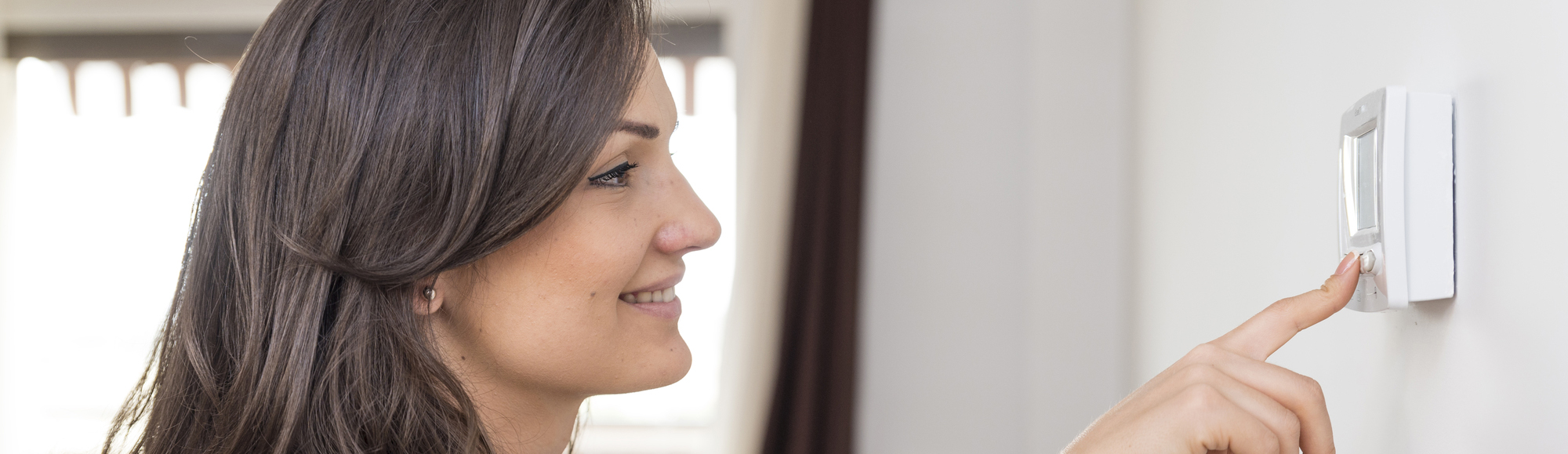 Woman adjusting thermostat