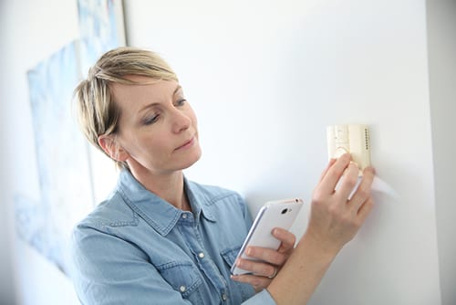 Woman inspecting thermostat