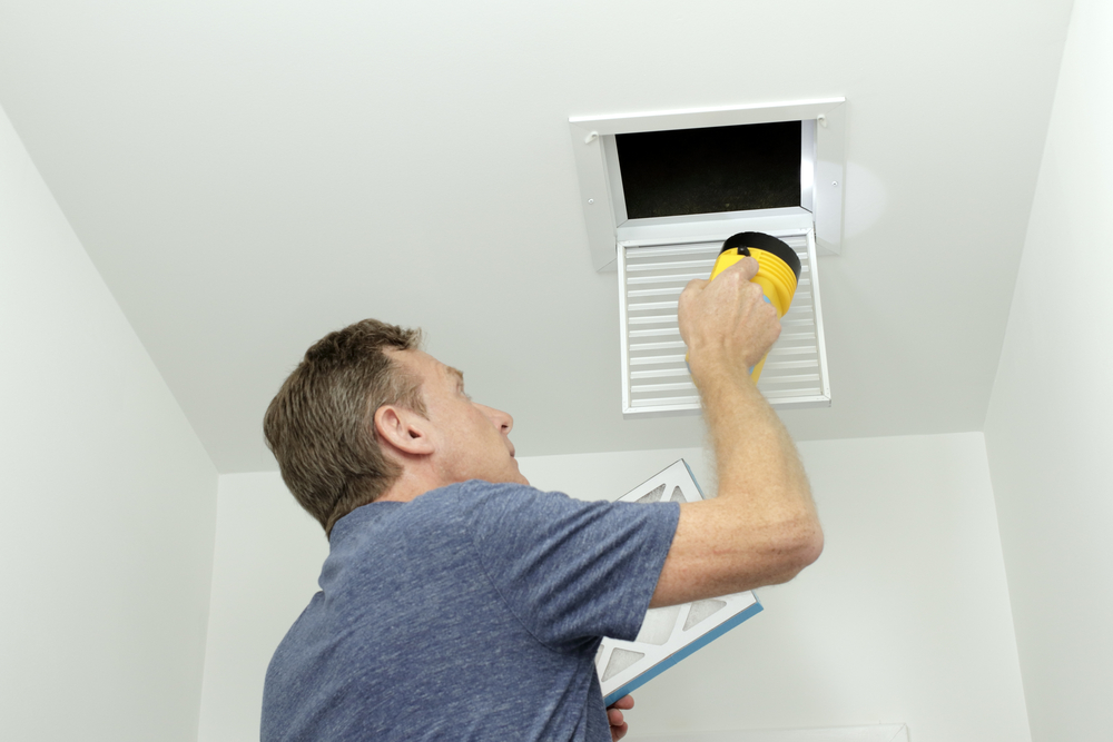 Man inspecting air ducts in a home