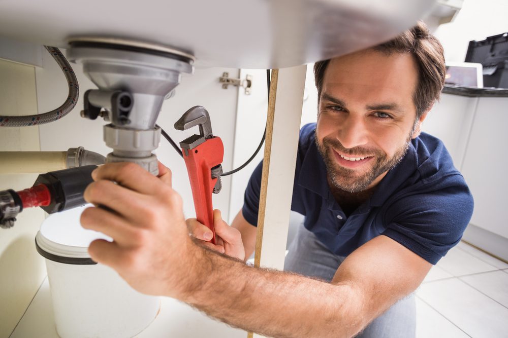 a plumber repairing a bathroom sink’s pipes