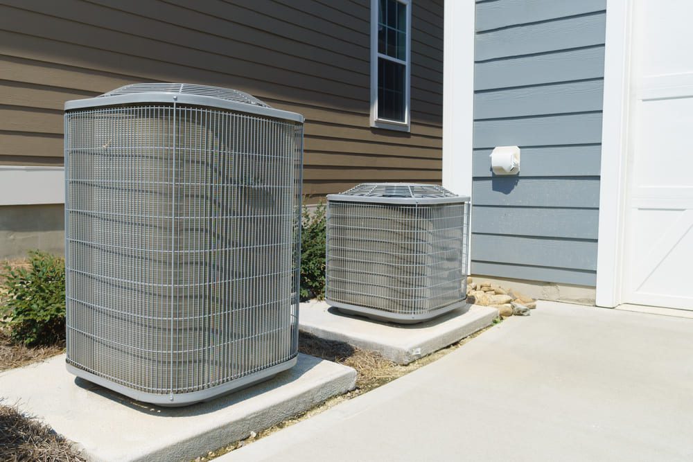 An outdoor air conditioning system sits next to a blue house.